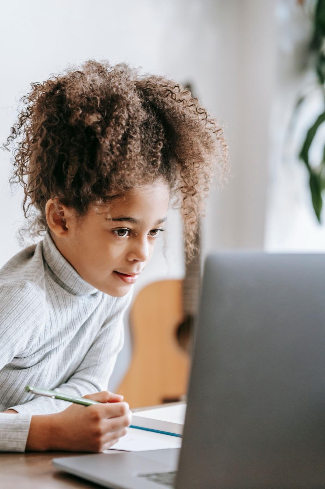A primary-school-age child concentrating on a lesson on a laptop